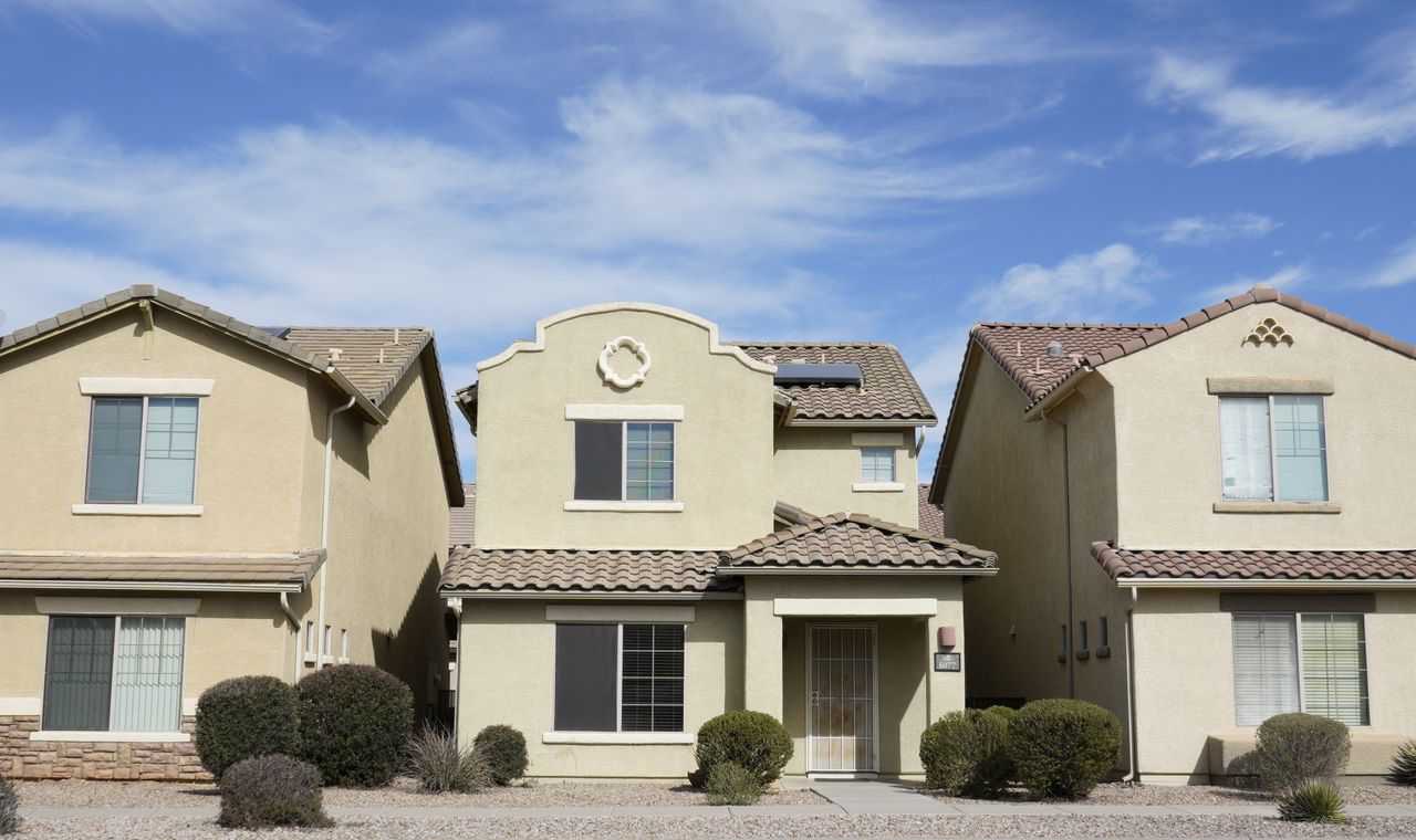 A row of stucco homes with tile roofs and gravel desert landscaping in a Tucson suburb, the remodel market FinTruction codes job by job