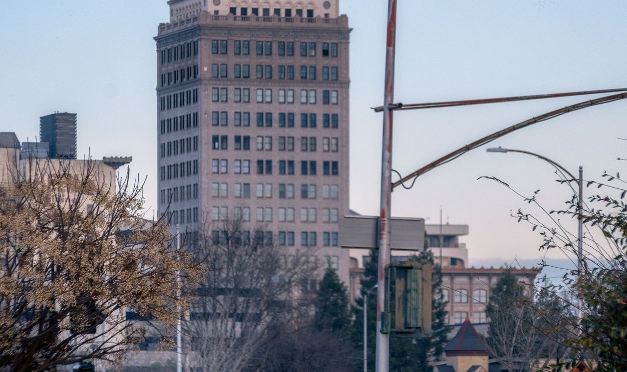 Downtown Fresno office tower behind bare winter trees in Valley haze, the market we support with job costing and WIP reporting