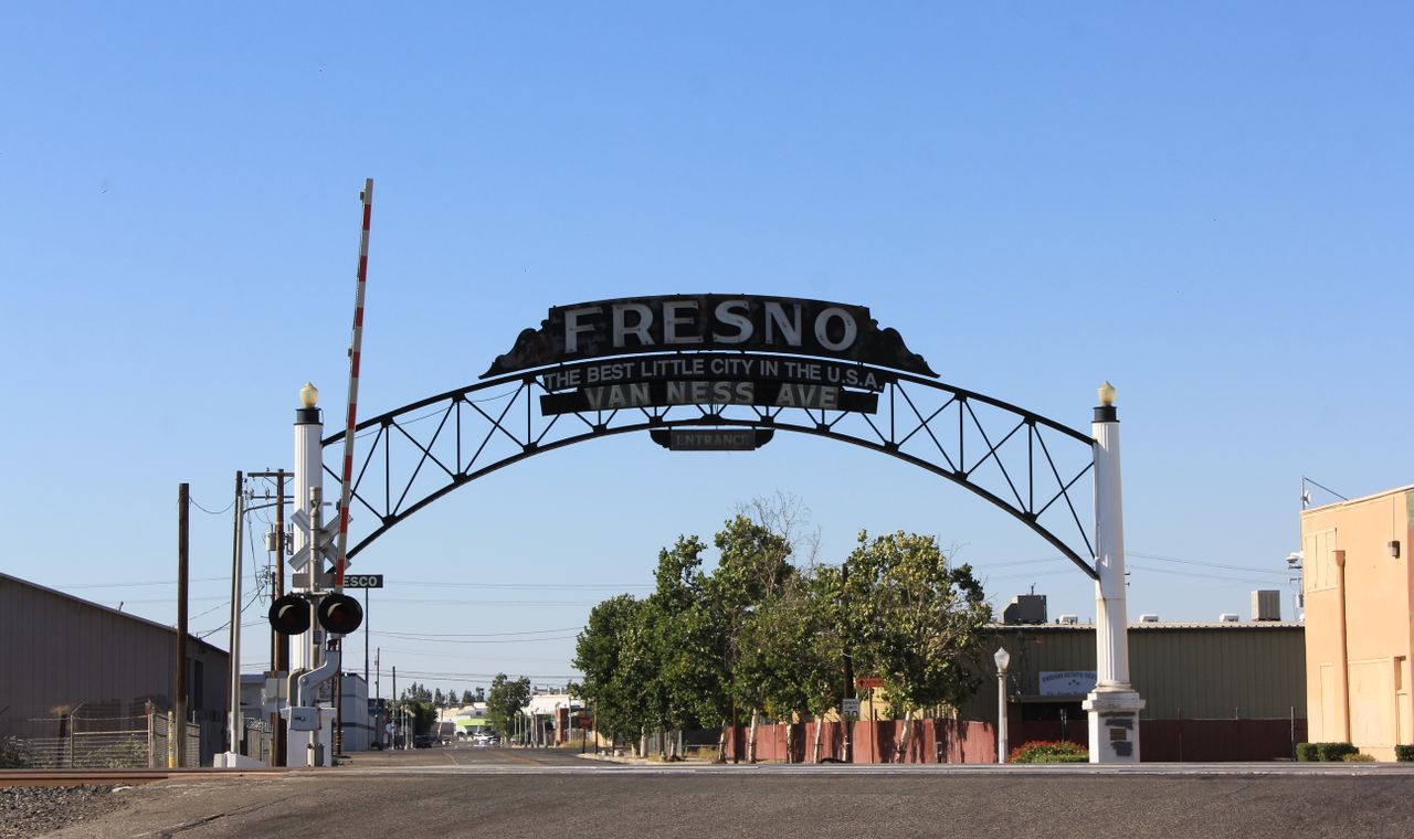 Steel Van Ness Avenue arch reading Fresno over an empty street and rail crossing, our Central Valley construction accounting market