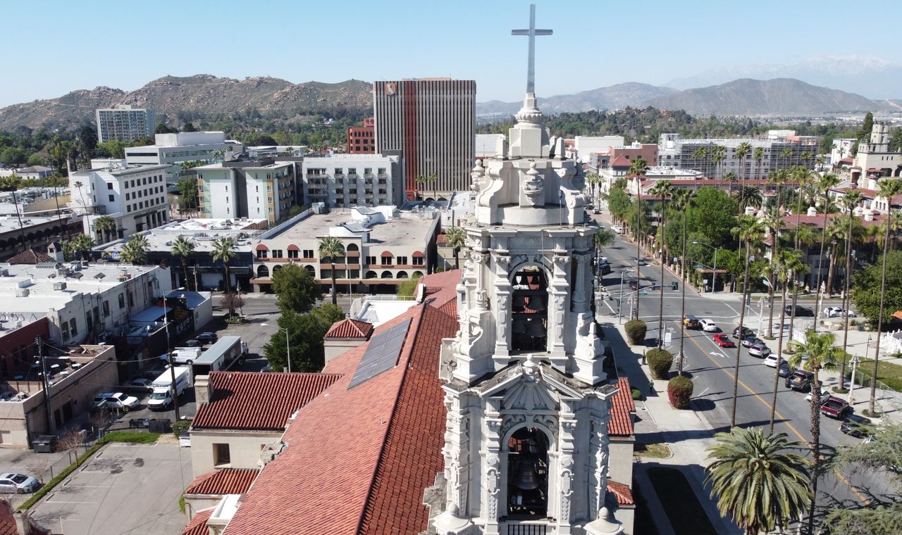 Aerial view over downtown Riverside with church bell towers, palms and the mountains behind, the Inland Empire market FinTruction supports with WIP reporting