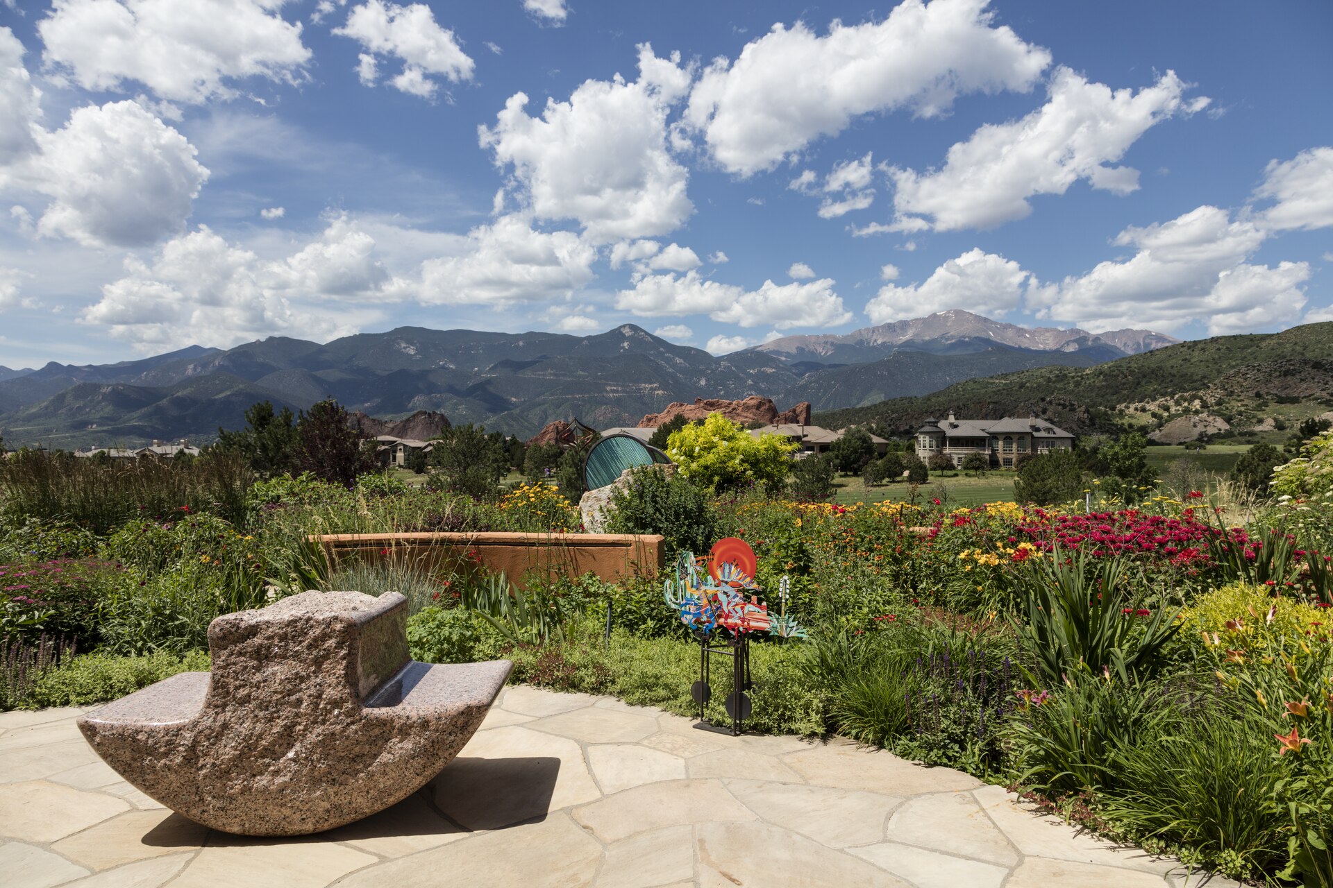Pikes Peak and the red rock formations of the Garden of the Gods rising behind a flower garden and golf course on the west side of Colorado Springs