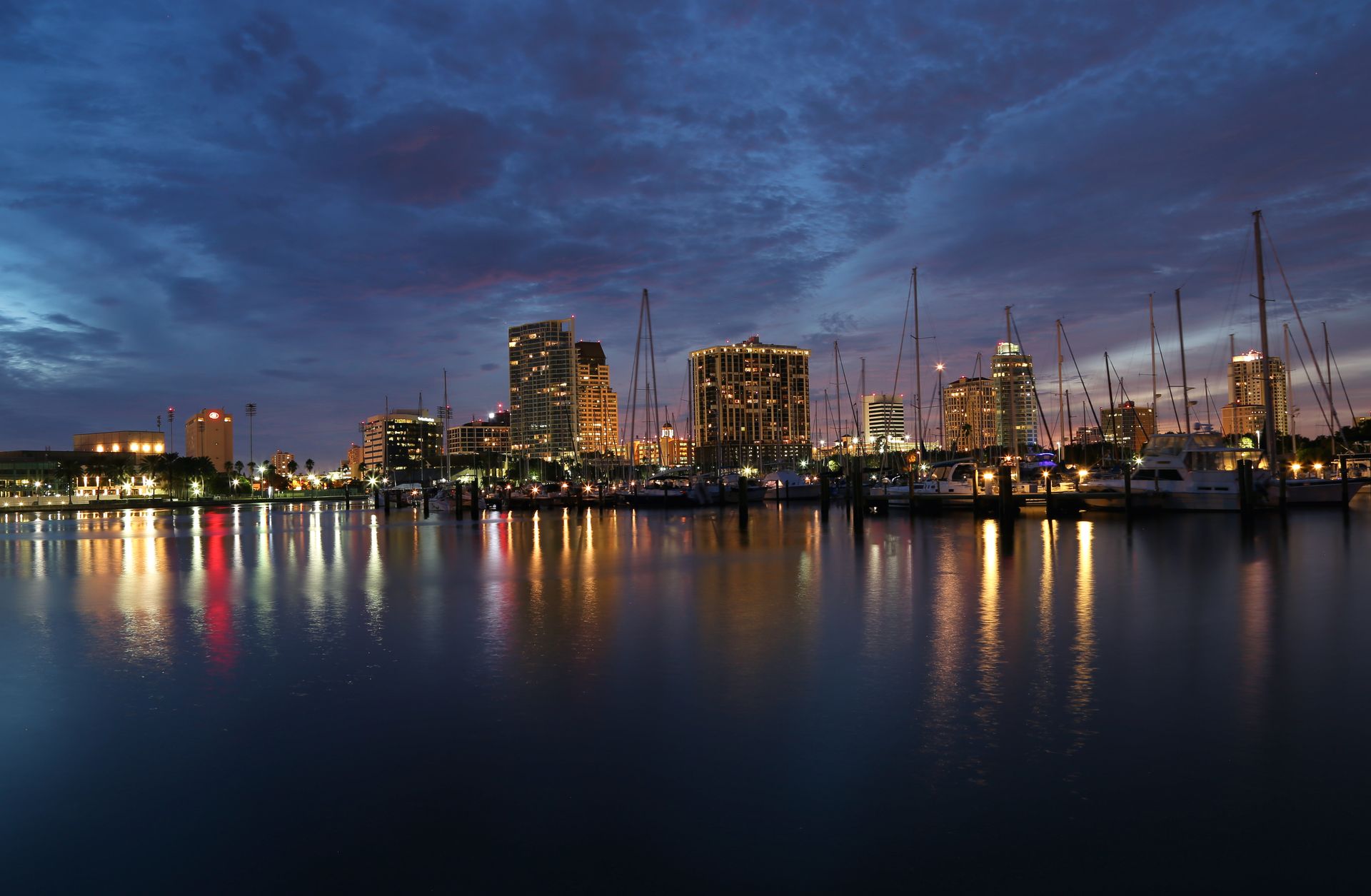 The downtown St. Petersburg skyline lit at dusk across the marina, condominium and office towers reflected in the water with sailboats moored in the foreground