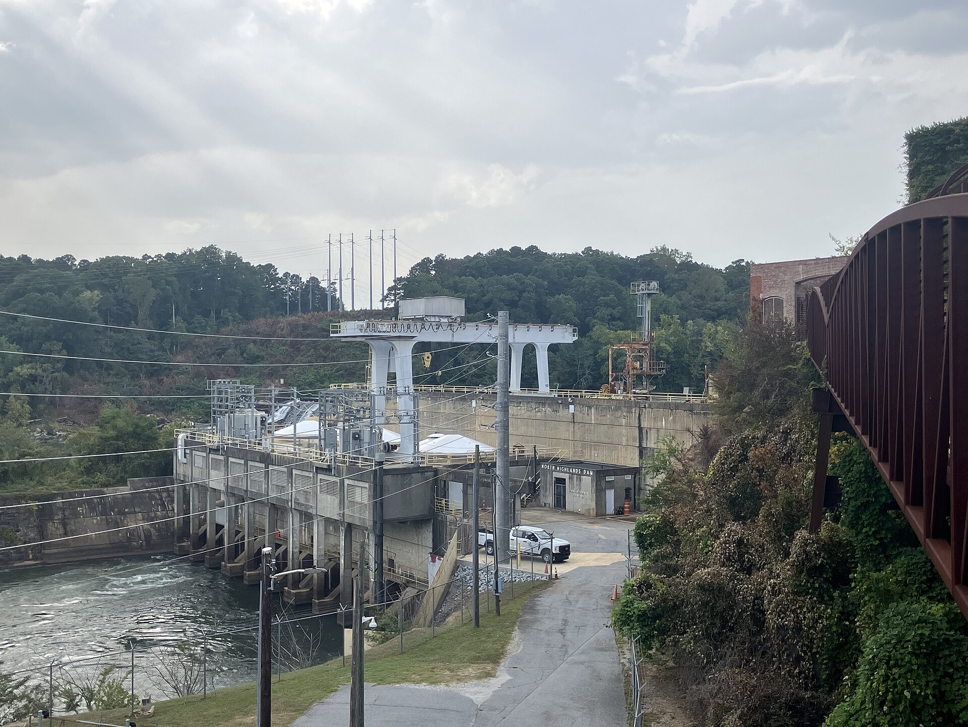North Highlands Dam and power station on the Chattahoochee at Columbus, concrete spillway and gate piers with a gantry crane and a steel truss bridge