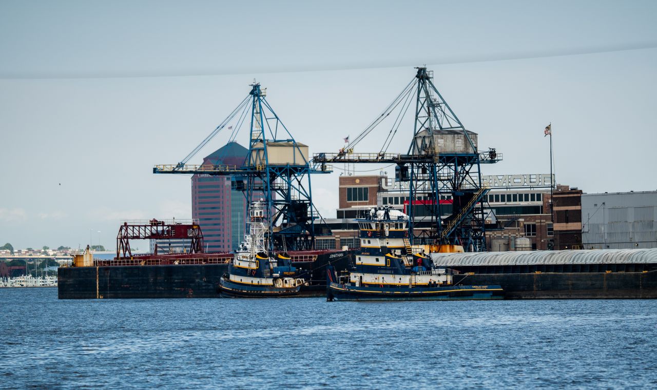 Blue gantry cranes, tugboats and barges on the Port of Baltimore waterfront, a marine contracting market with weekly certified payroll