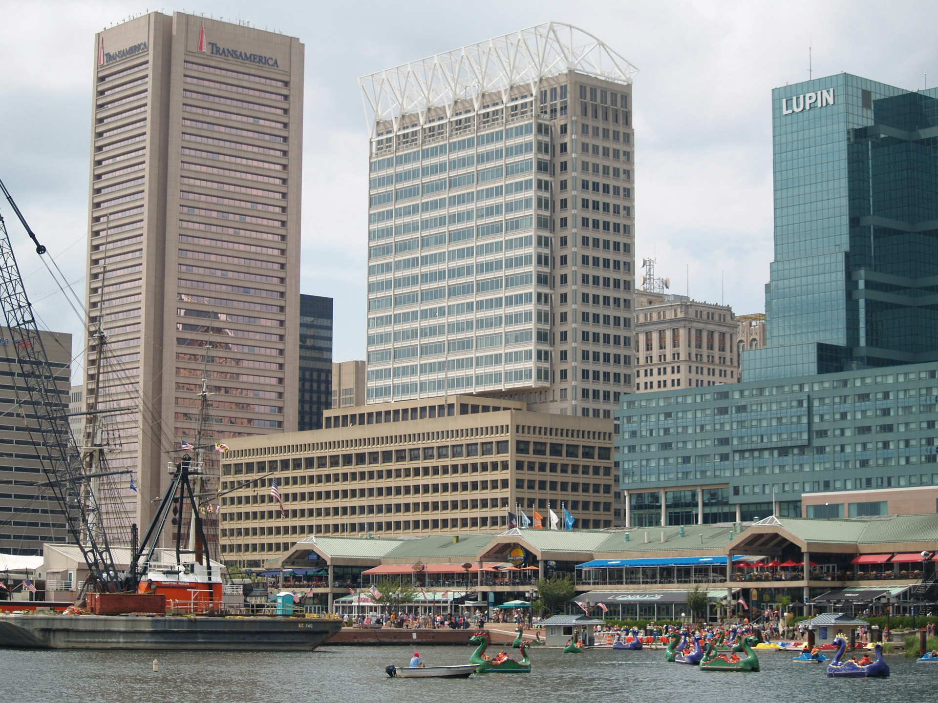 Baltimore Inner Harbor with the pentagonal Transamerica tower, Harborplace pavilions, a crane barge and dragon paddle boats, the anchor of the Maryland construction market
