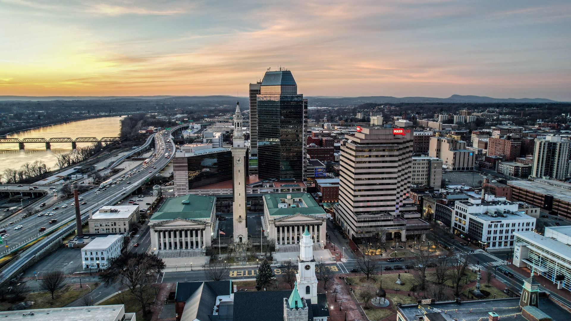Aerial view of downtown Springfield, Massachusetts at sunset, the Campanile clock tower and Municipal Group in the foreground with office towers, the elevated interstate and the Connecticut River behind