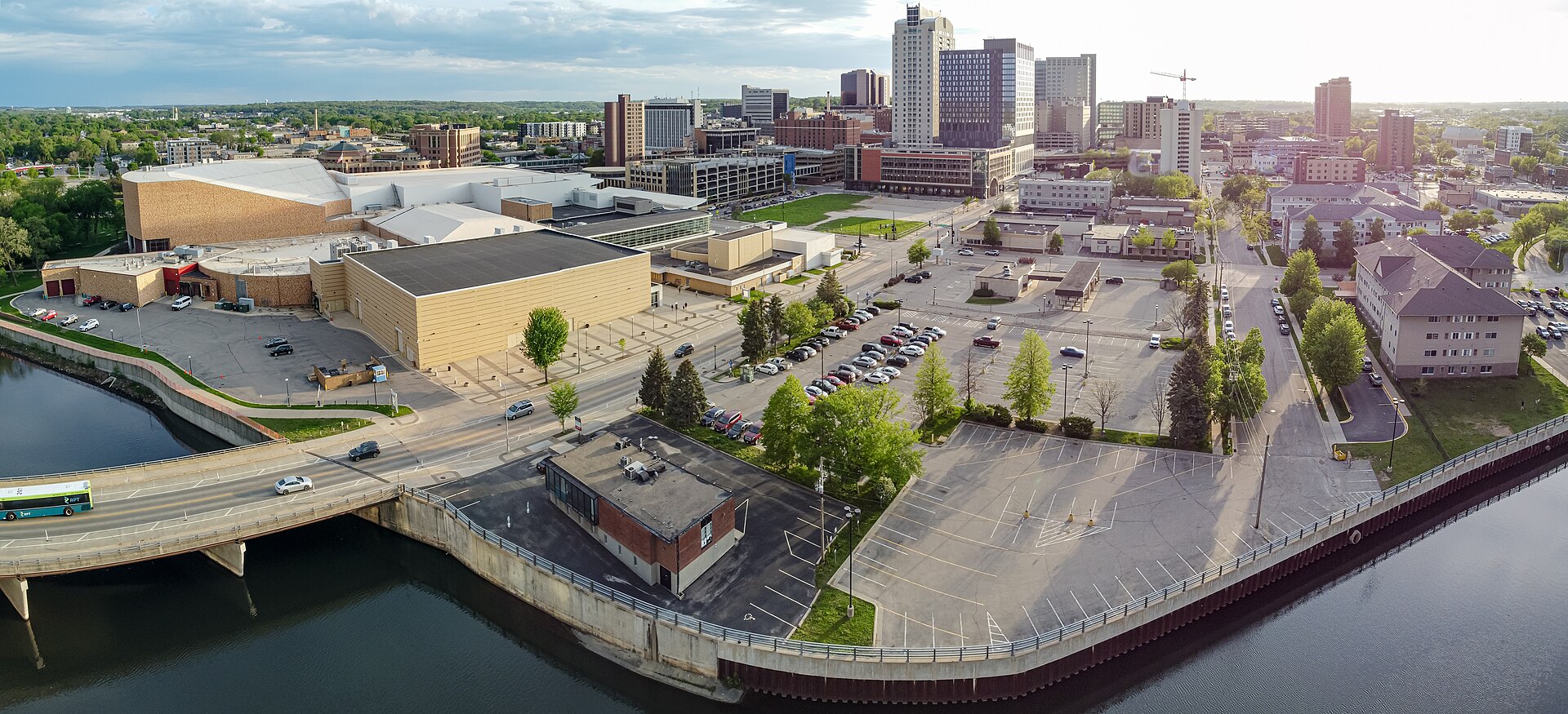 Aerial view over downtown Rochester, Minnesota at golden hour with the Zumbro River, civic center roofs, downtown towers and a yellow tower crane