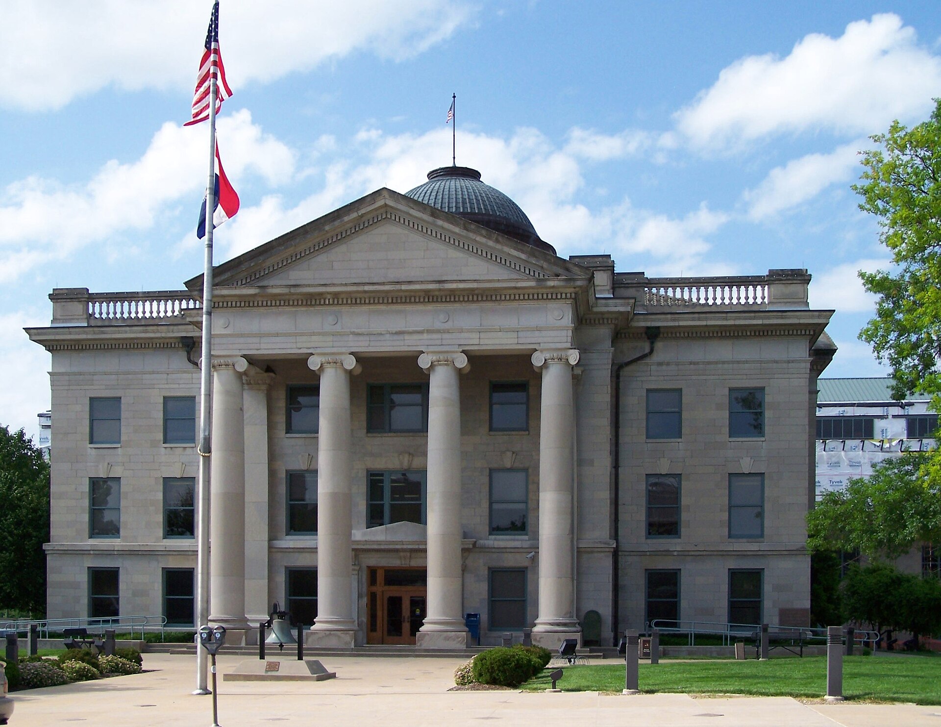The Boone County Courthouse in downtown Columbia, Missouri, a limestone building with Ionic columns and a green dome, the US and Missouri flags flying out front
