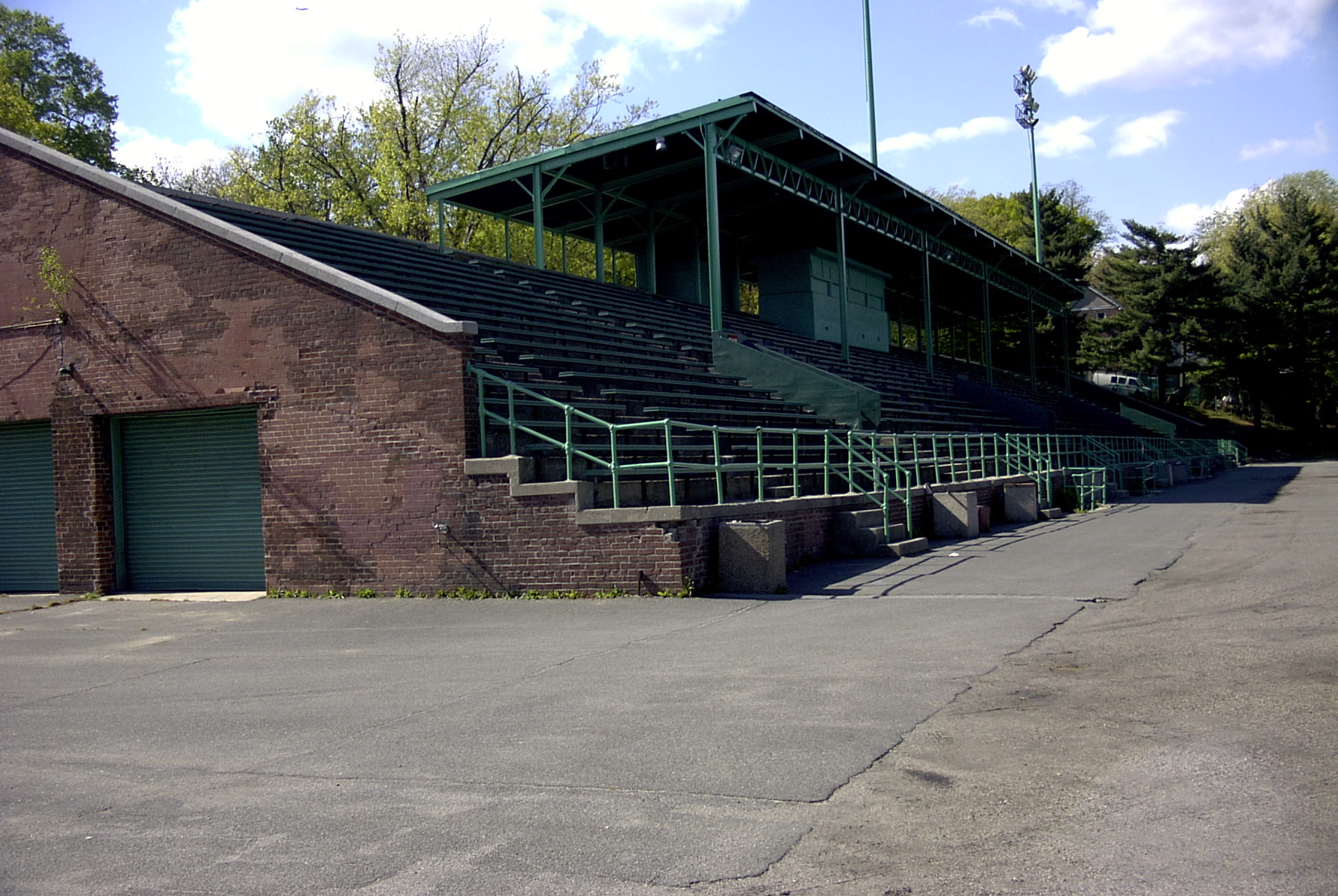 The grandstand at Memorial Field in Mount Vernon, tiered concrete seating under a green steel canopy above an old brick service building