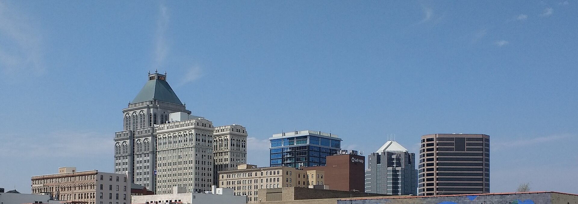 Downtown Greensboro skyline seen from the depot, the green-roofed Jefferson Standard tower rising over lower brick blocks under a clear sky