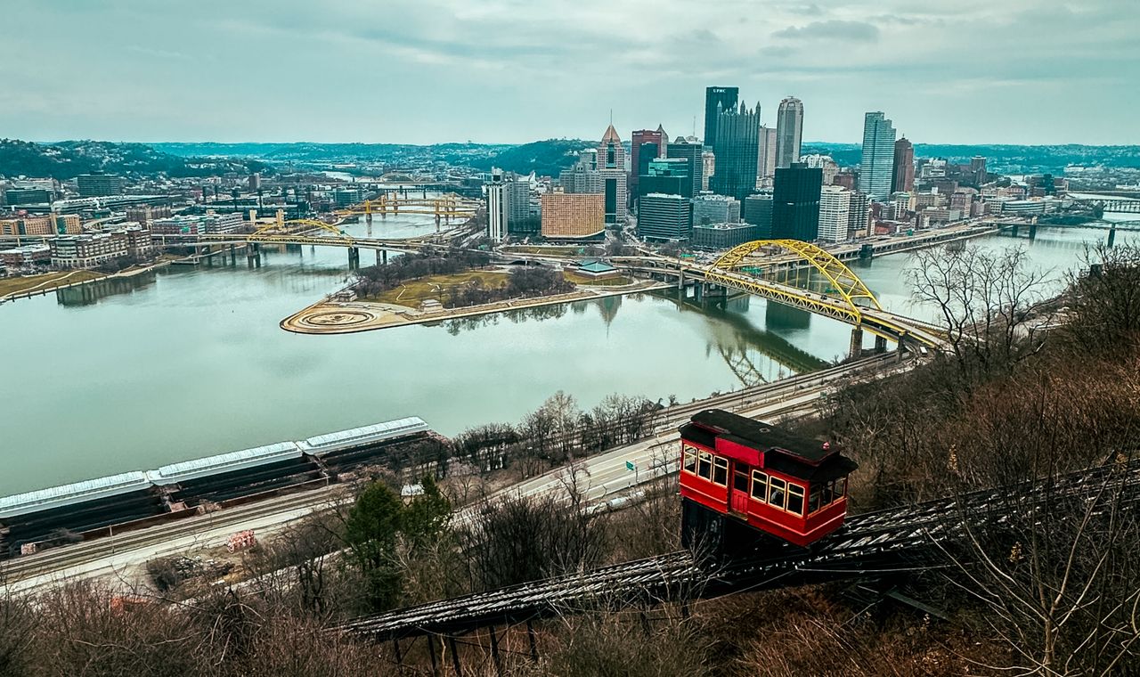 A red incline car above downtown Pittsburgh and its river bridges, the hillside terrain FinTruction's contractor bookkeeping clients build on