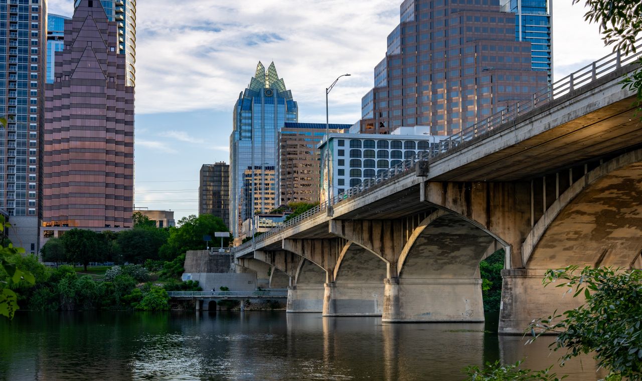 Downtown Austin high-rises beside a concrete arch bridge over Lady Bird Lake, the market FinTruction supports with contractor bookkeeping