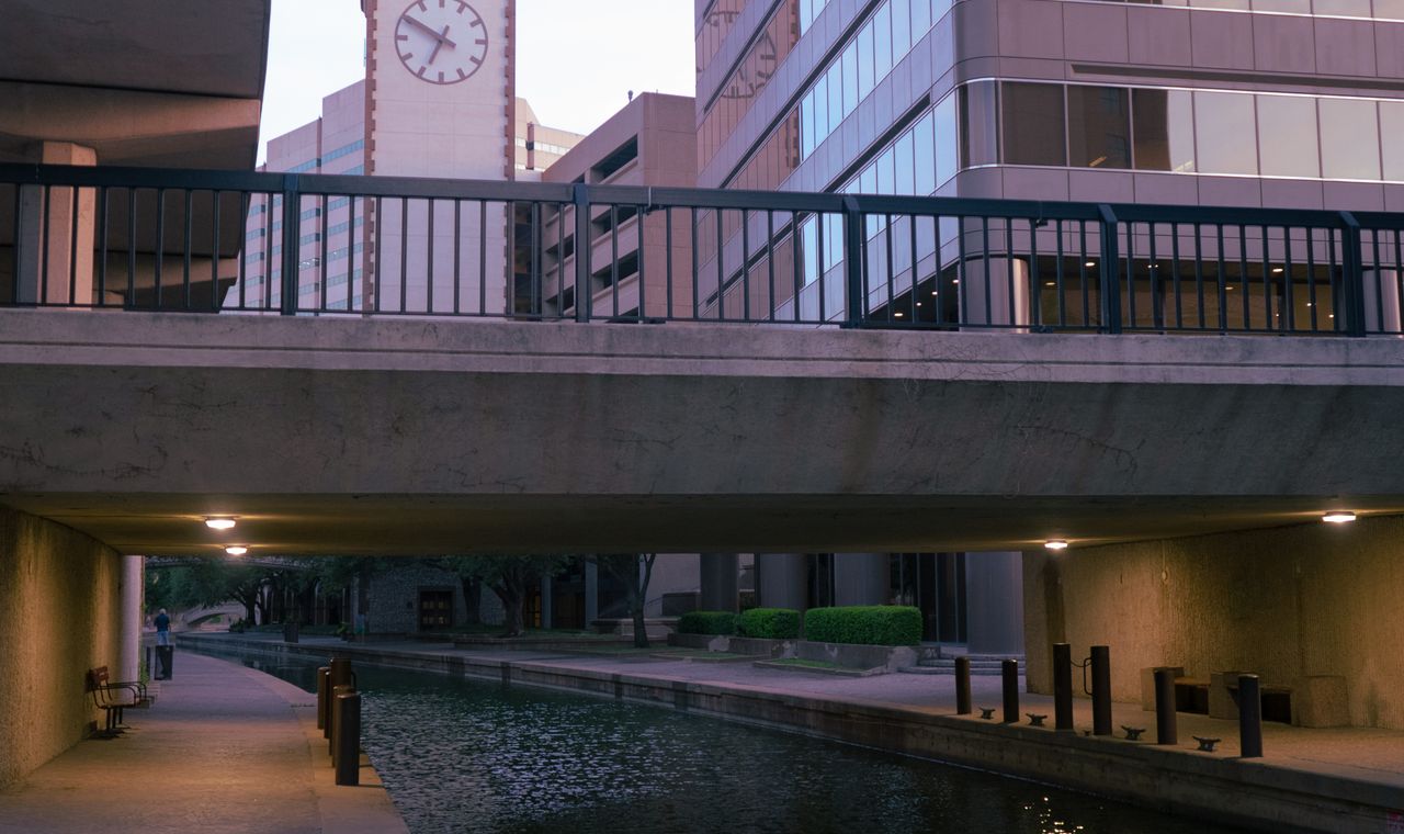 A pedestrian bridge crossing the Las Colinas canal in Irving with a clock tower and office towers behind, the market FinTruction serves with construction accounting