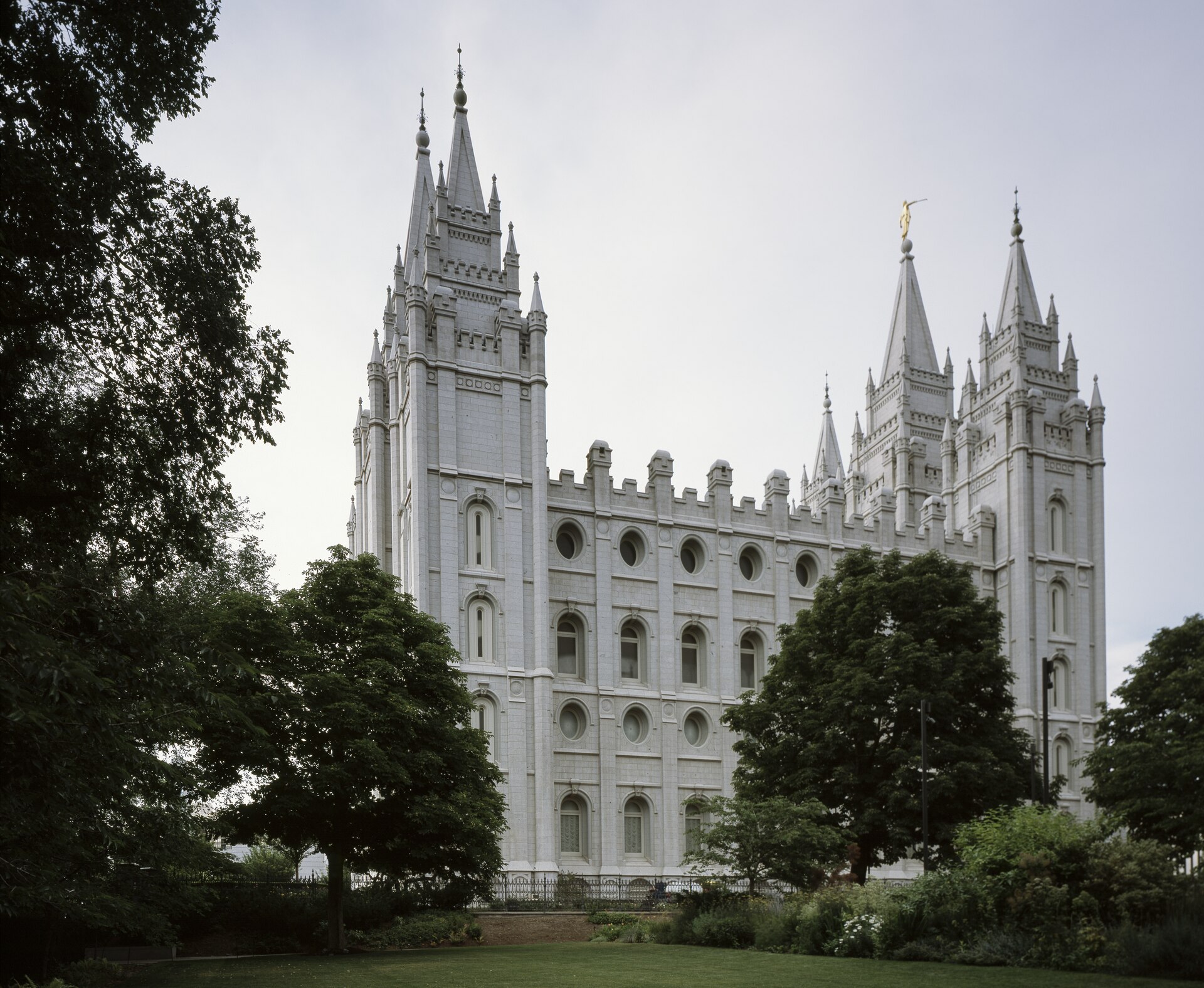 The granite Salt Lake Temple on Temple Square in downtown Salt Lake City, its six spires and gold Angel Moroni statue rising above the trees of the walled grounds