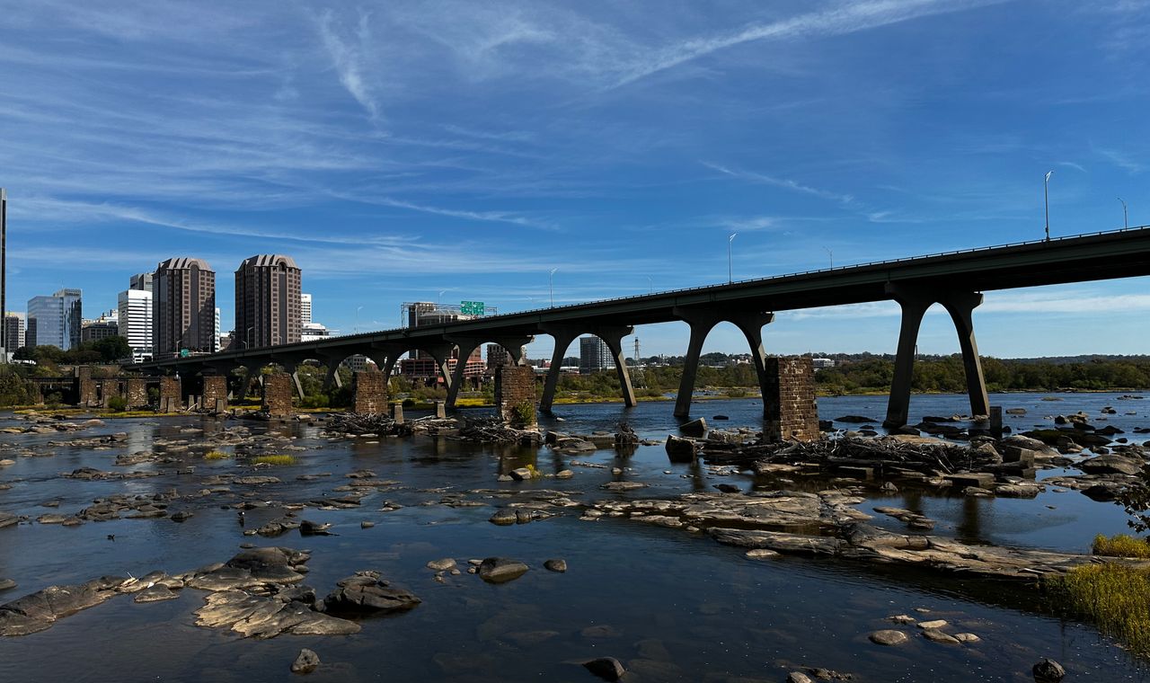 The James River running over exposed rock beneath the Manchester Bridge with downtown Richmond towers behind it, the state capital market FinTruction supports with job costing and WIP reporting