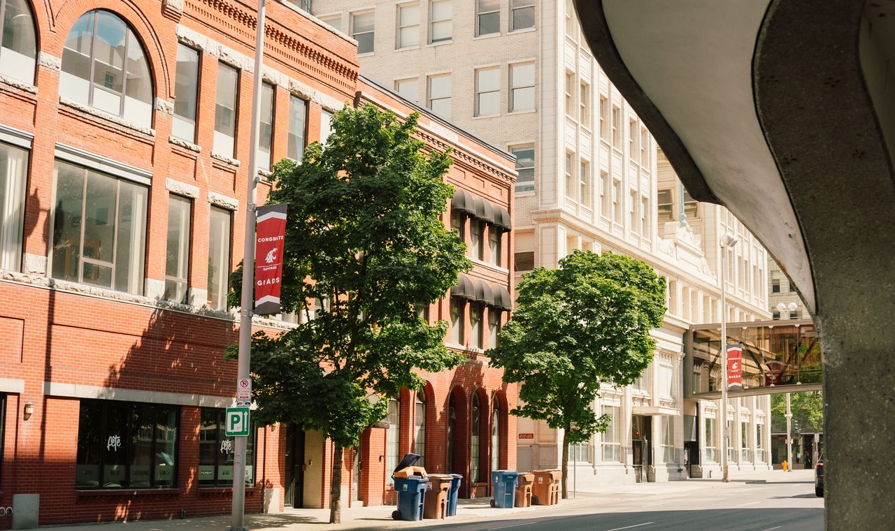 Red brick historic storefronts and street trees on a quiet downtown Spokane block, the Inland Northwest market FinTruction serves with construction accounting