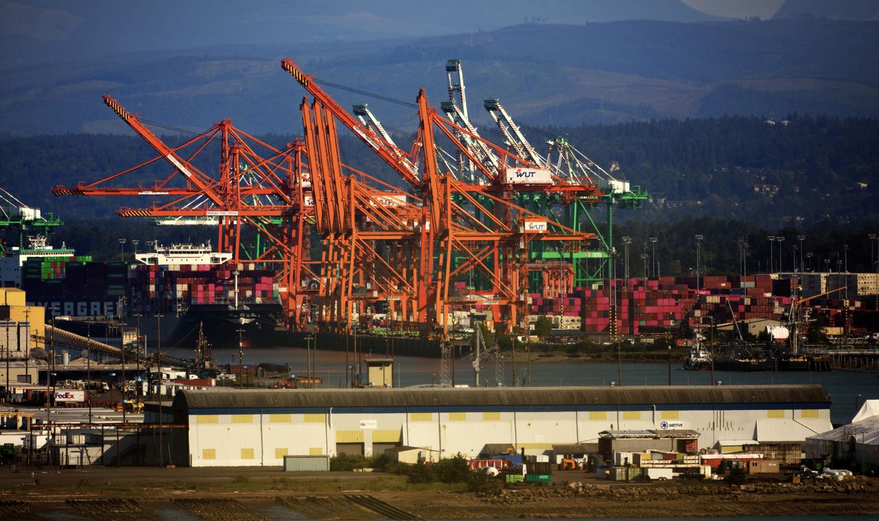 Orange container gantry cranes and stacked containers at a Port of Tacoma terminal, the tideflats market FinTruction keeps contractor books for